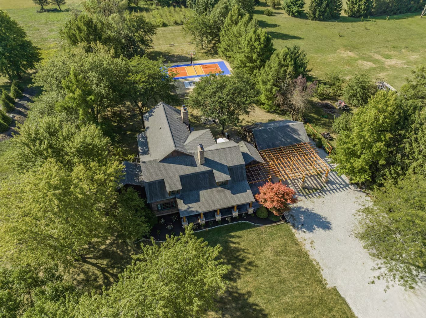 Aerial view of a wooded Indiana short-term rental estate with a sport court